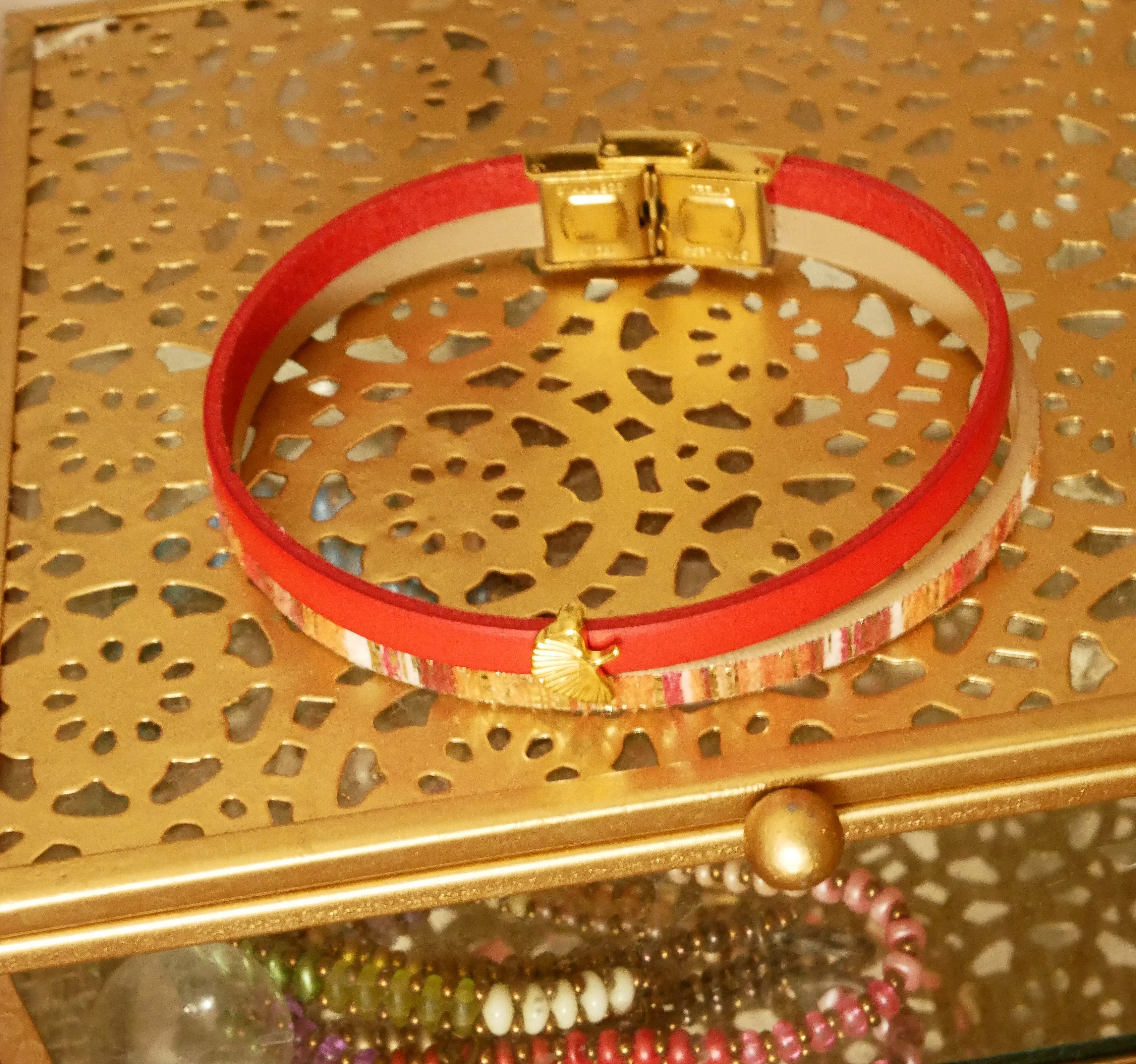 Bracelet duo cuir rouge et or avec motif ginkgo doré.