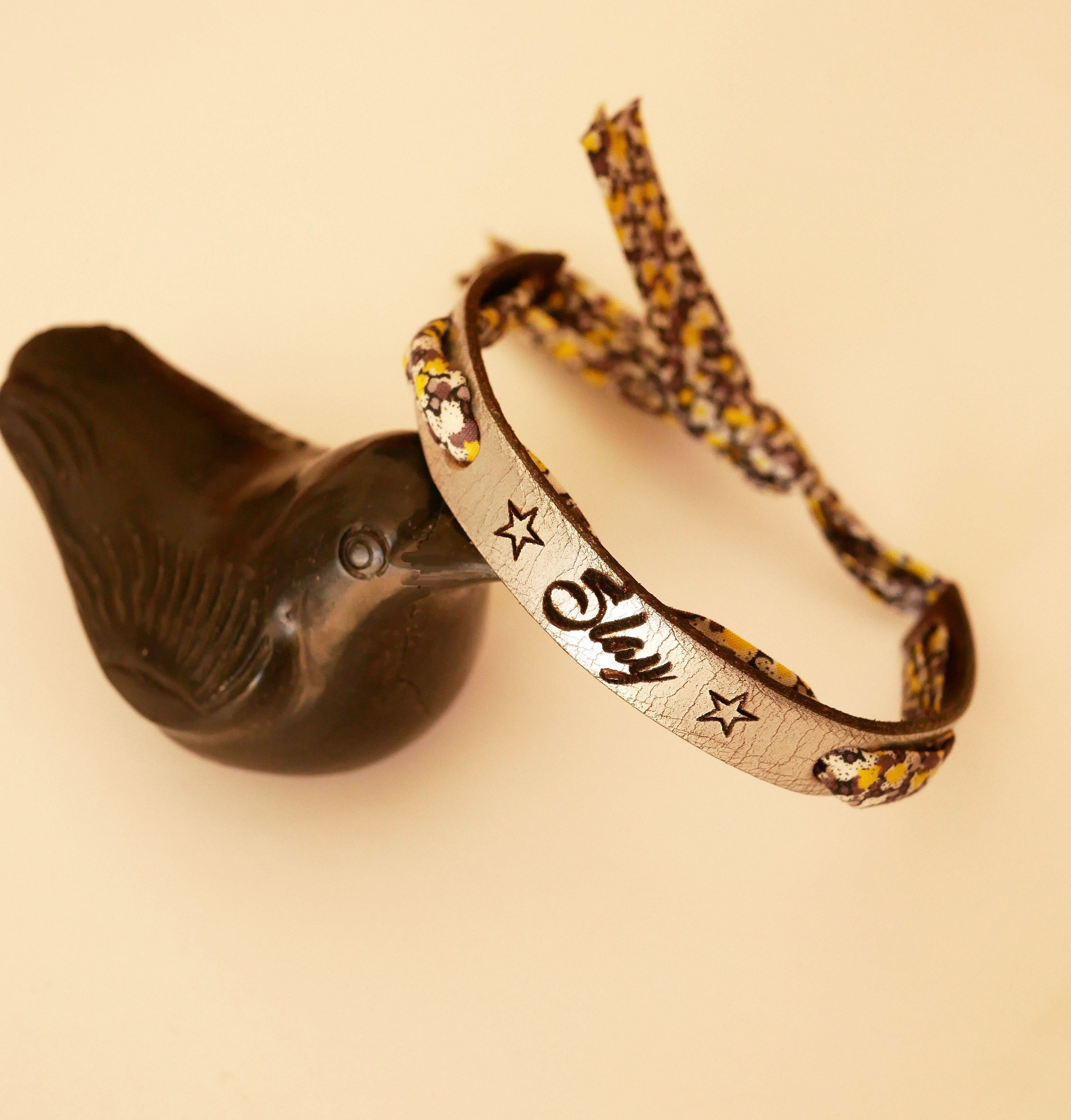 Bracelet personnalisable en cuir avec inscription et ruban fleuri.