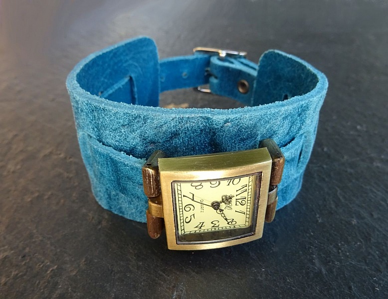 Montre carrée avec bracelet manchette en cuir bleu.