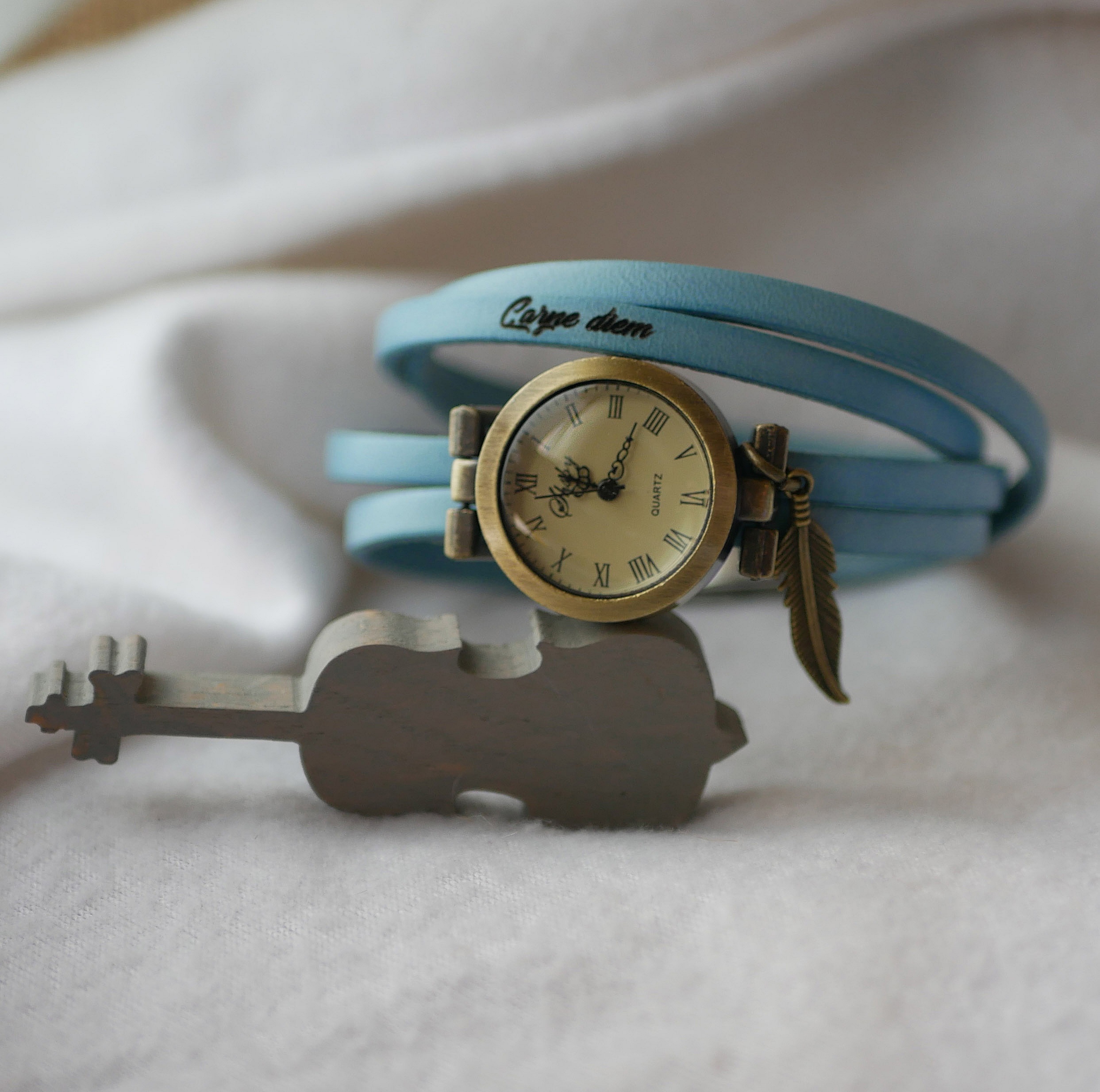 Montre bracelet personnalisable bleu clair avec breloque plume.